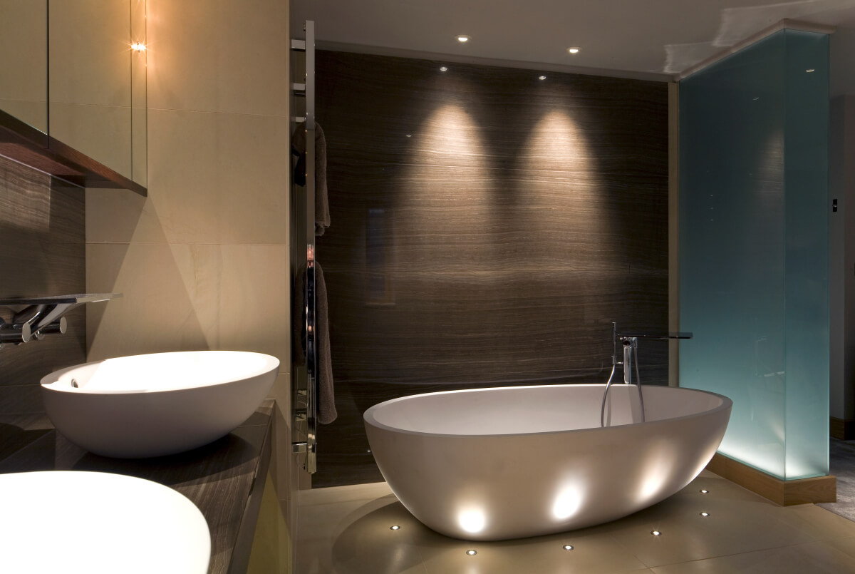 Ground recessed LED accent lighting in a bathroom floor uplighting a freestanding bath